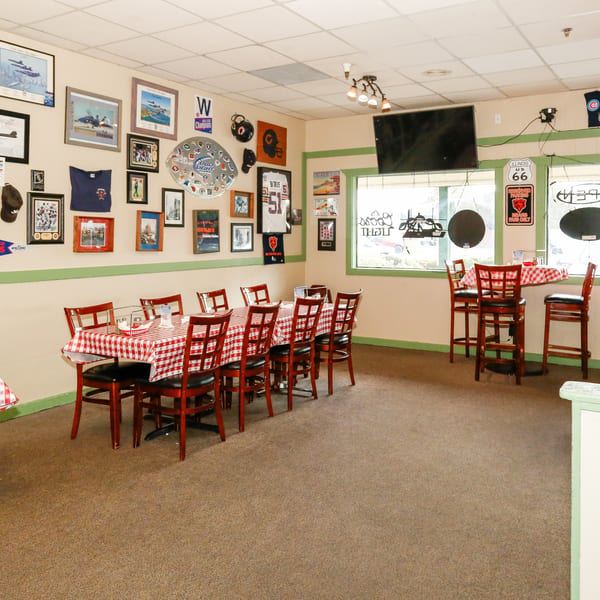 Restaurant interior with red and white checkered tables, bar stools, and sports memorabilia on the walls.