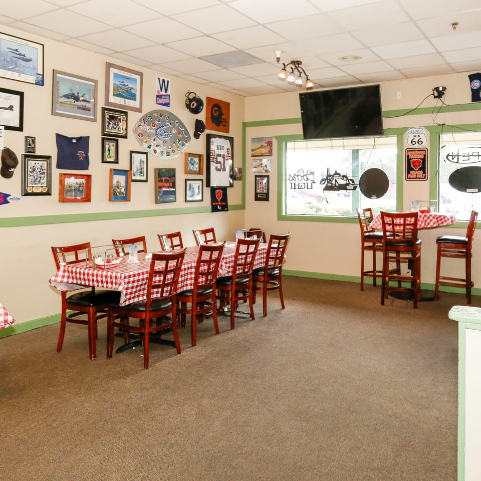 Restaurant interior with red and white checkered tables, bar stools, and sports memorabilia on the walls.